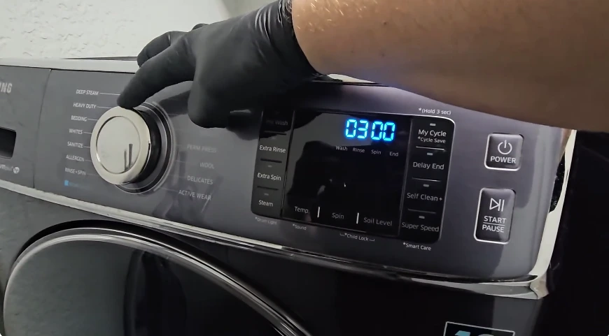 Technician checking a washer timer and wiring behind the control panel